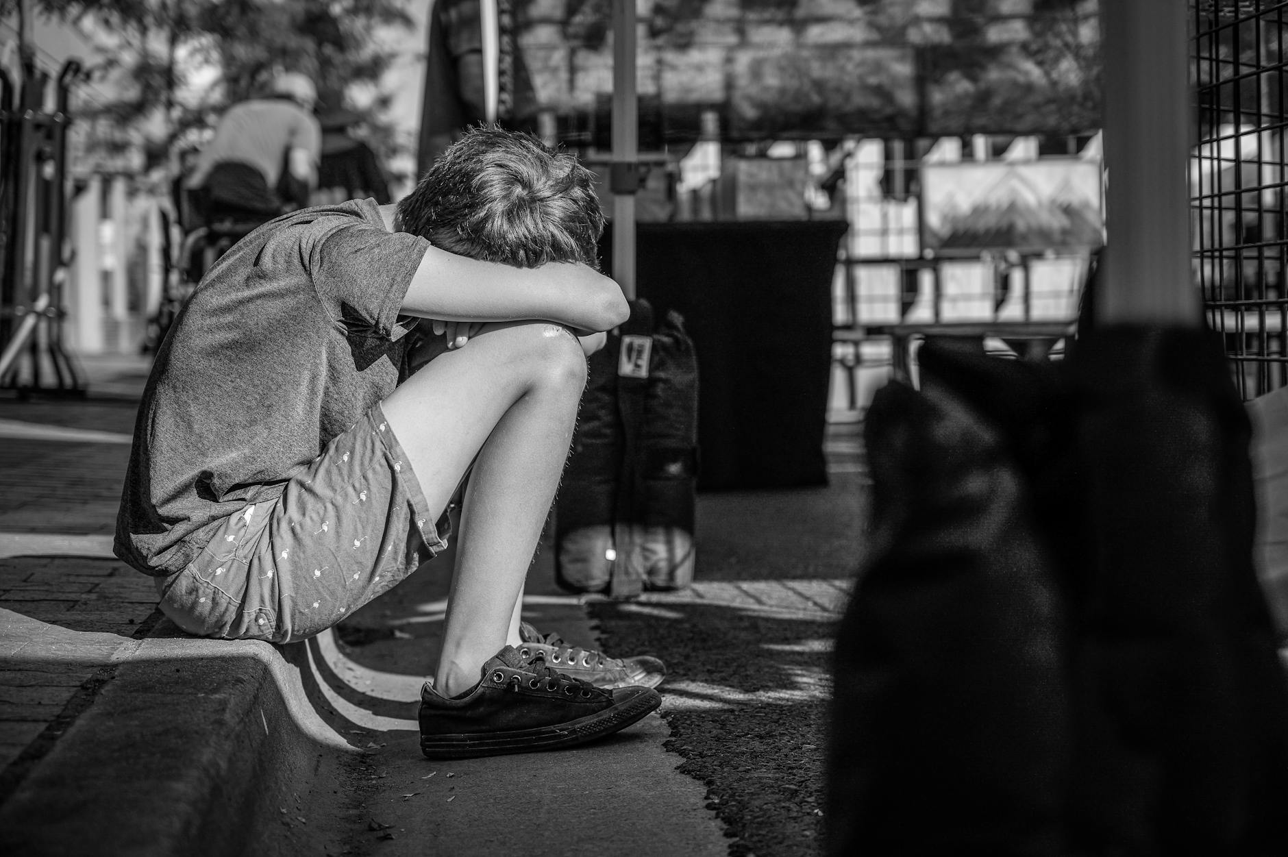 monochrome photo of person sitting on curb